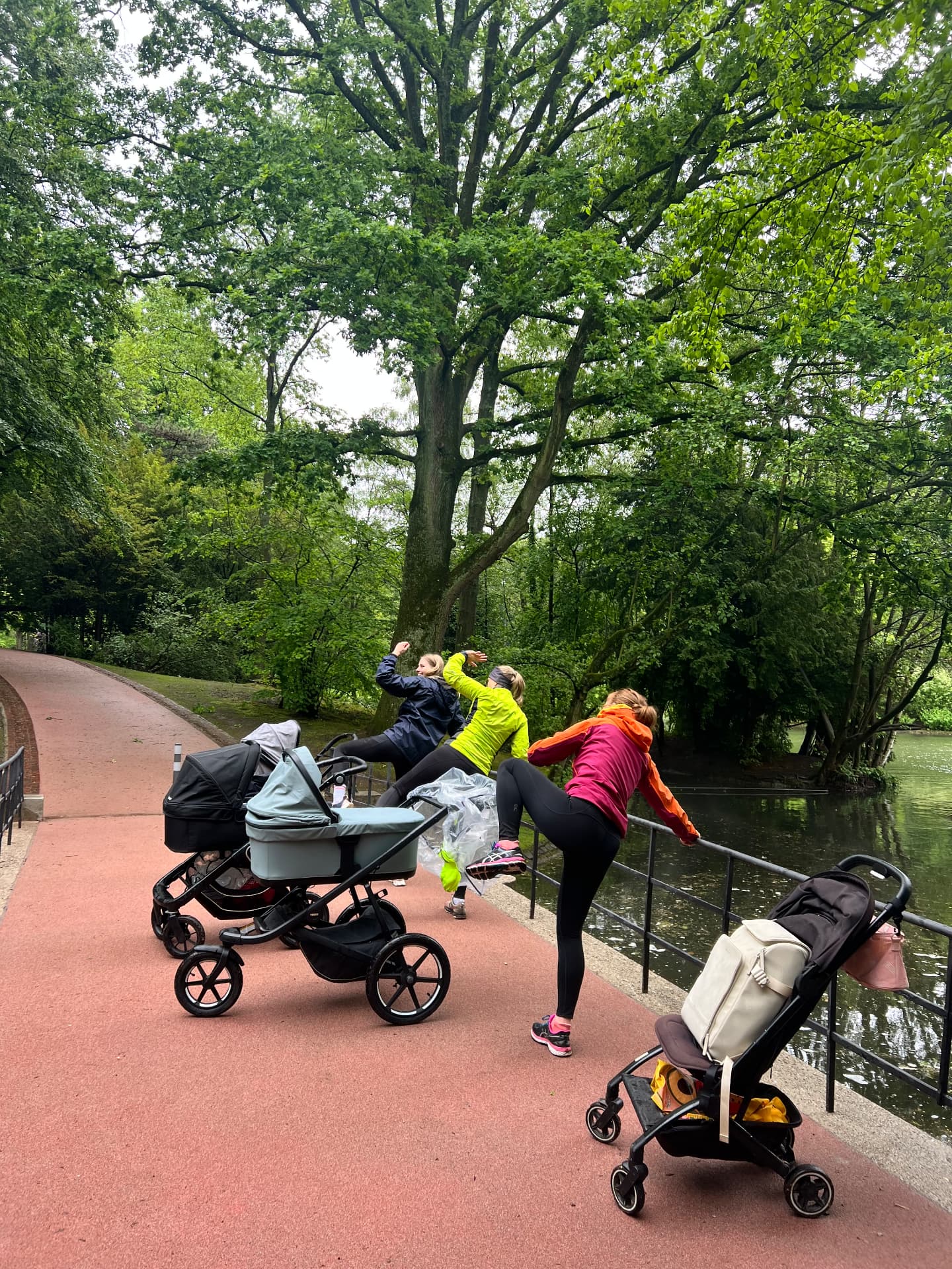 Mama bei sanfter Bewegung auf der Matte im Stadtpark, Baby daneben